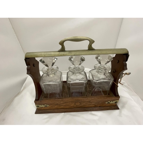 13 - A VINTAGE MAHOGANY AND BRASS TANTALUS WITH THREE MATCHING DECANTERS AND KEY