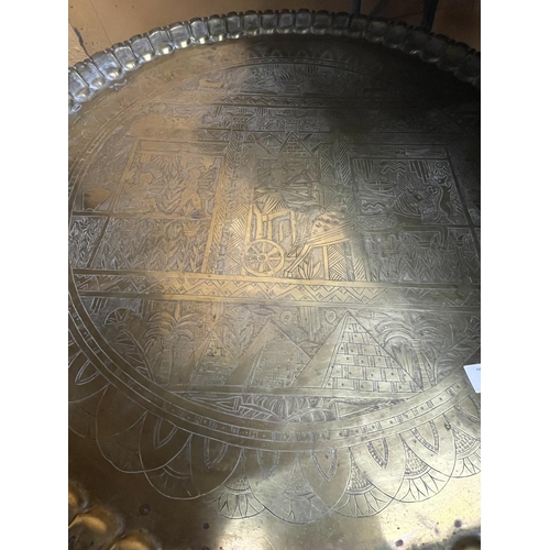 38 - A LARGE SIX LEGGED FOLDING TABLE WITH BRASS TOP  DEPICTING EGYPTIAN LIFE DIAMETER 73CM