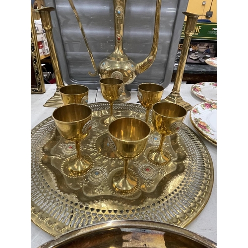 4 - A BRASS AND JEWELLED DALLAH AFTABA POT AND GOBLETS ON TRAY TOGETHER WITH TWO BRASS CANDLESTICKS AND ... 