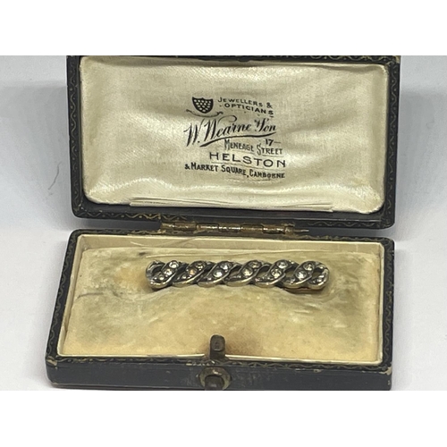 634 - A YELLOW METAL AND TWELVE STONE PIN WITH A PRESENTATION BOX