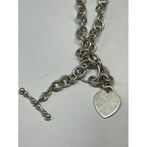 543 - A SILVER T BAR NECKLACE WITH HEART CHARM IN A PRESENTATION BOX