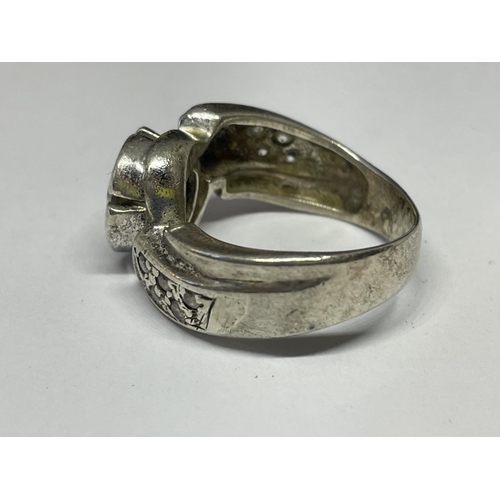 586 - A SILVER RING WITH A LARGE CENTRAL CLEAR STONE AND CLEAR SONES ON TWISTED SHOULDERS SIZE O/P IN A PR... 