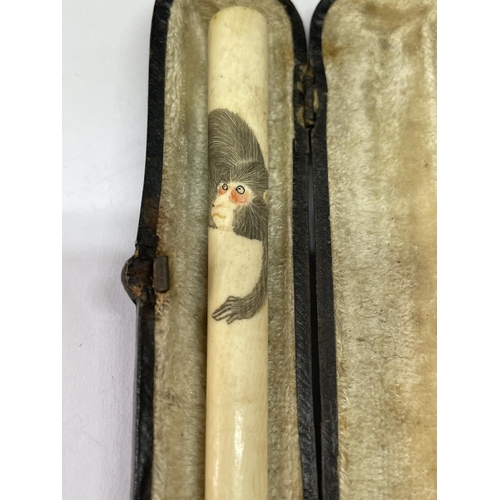 781 - A CASED BONE CHEROOT HOLDER WITH A MONKEY DESIGN