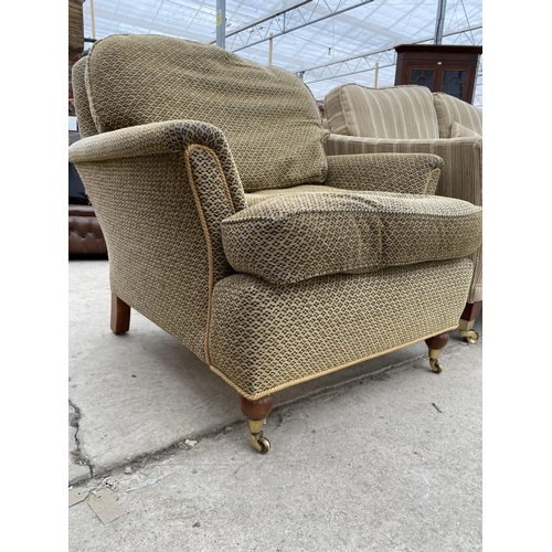 2428 - A MODERN EASY CHAIR ON TURNED FRONT LEGS WITH BRASS CASTERS