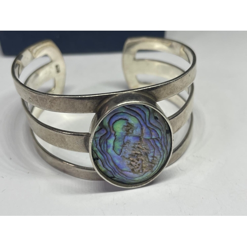 693 - A SILVER BANGLE WITH LARGE PEARLISED STONE IN A PRESENTATION BOX