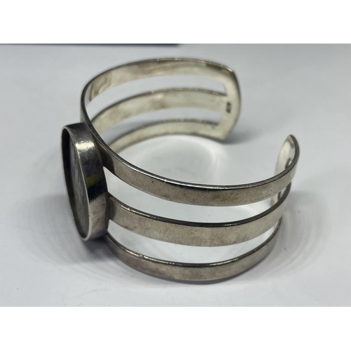 693 - A SILVER BANGLE WITH LARGE PEARLISED STONE IN A PRESENTATION BOX