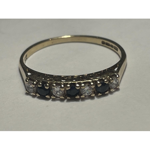 613 - A 9 CARAT GOLD RING WITH THREE SAPPHIRES AND FOUR CUBIC ZIRCONIAS IN A LINE SIZE P