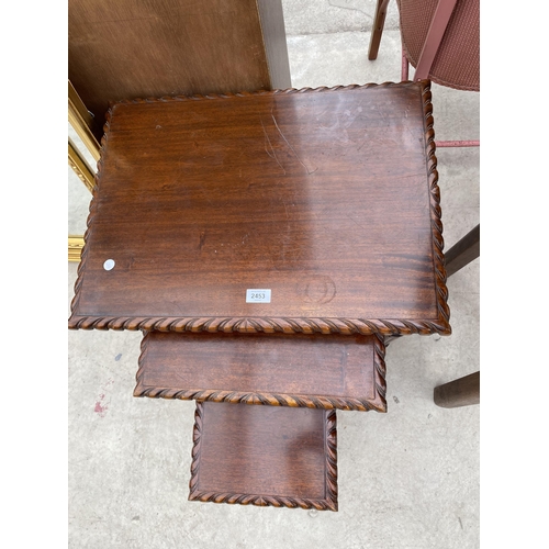 2453 - A NEST OF THREE HARDWOOD TABLES WITH ROPE EDGES ON TURNED AND FLUTED LEGS