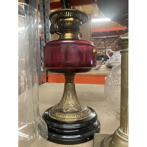 996 - TWO BRASS BASED OIL LAMPS, ONE WITH A CRANBERRY GLASS MIDDLE, FOUR CHIMNEYS AND TWO GLASS SHADES