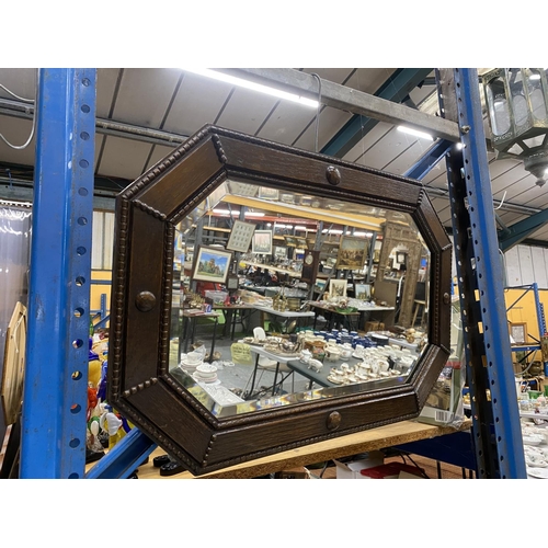 543 - AN OAK FRAMED ARTS AND CRAFTS STYLE MIRROR IN AN OCTAGONAL SHAPE WITH BEVELLED GLASS