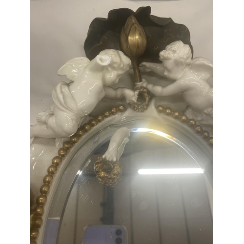 24 - A WHITE AND GILDED CERAMIC MIRROR WITH CHERUB, LILY AND LEAF DESIGN (A/F CHERUBS ARM)