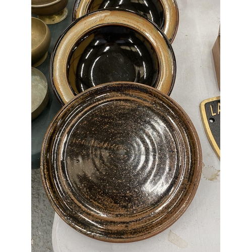 112 - A QUANTITY OF STUDIO POTTERY BOWLS AND PALTES WITH A BROWN GLAZE