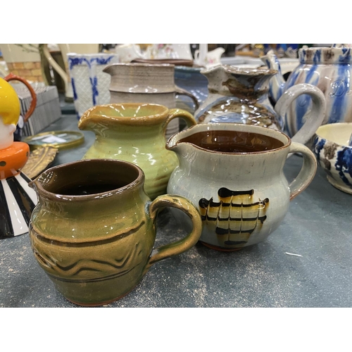 118 - A QUANTITY OF STUDIO POTTERY JUGS IN VARIOUS COLOURS - SOME SIGNED TO THE BASE