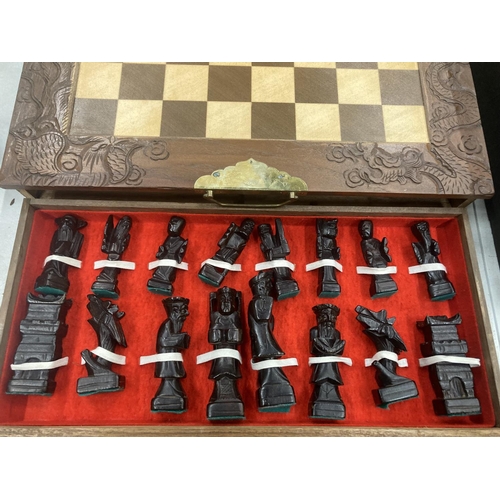 203 - A CHESS SET WITH A WOOD AND RESIN TOP AND WOODEN CHESS PIECES CONTAINED IN DRAWERS, WITH BRASS HINGE... 