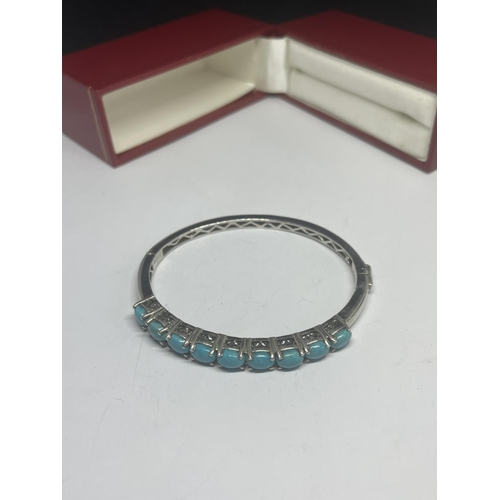 554 - A MARKED SILVER BANGLE WITH A LINE OF NINE NAVAJO STYLE STONES IN A PRESENTATION BOX