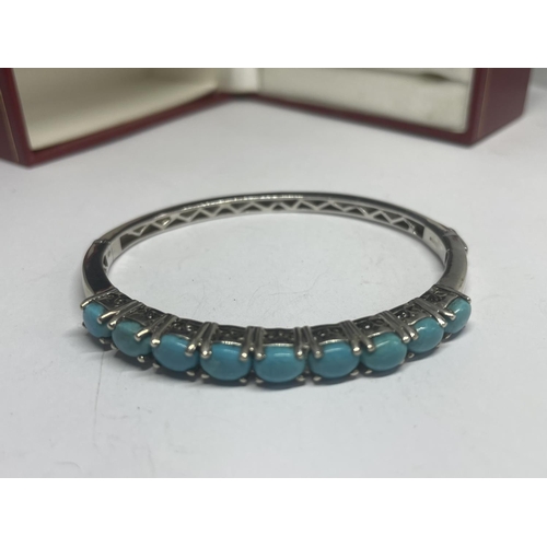 554 - A MARKED SILVER BANGLE WITH A LINE OF NINE NAVAJO STYLE STONES IN A PRESENTATION BOX