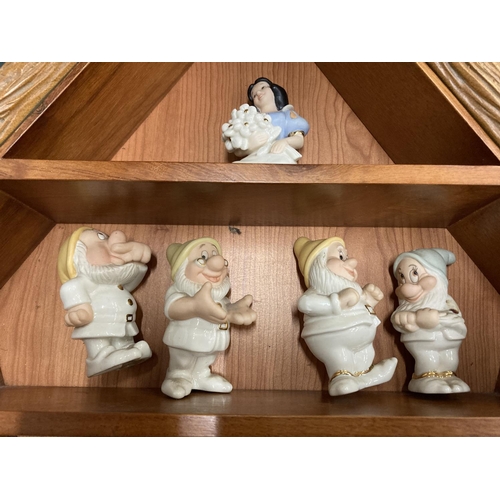 140 - A WOODEN HOUSE SHAPED DISPLAY CASE CONTAINING LENNOX DISNEY MODELS OF SNOW WHITE AND THE SEVEN DWARF... 