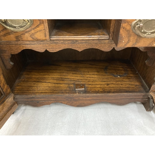 95 - A VINTAGE OAK SMOKERS CABINET WITH BEVELLED GLASS DOORS, BRASS HANDLED DRAWERS, GALLERIED TOP, ETC H... 