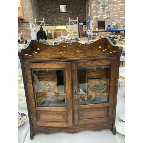 95 - A VINTAGE OAK SMOKERS CABINET WITH BEVELLED GLASS DOORS, BRASS HANDLED DRAWERS, GALLERIED TOP, ETC H... 