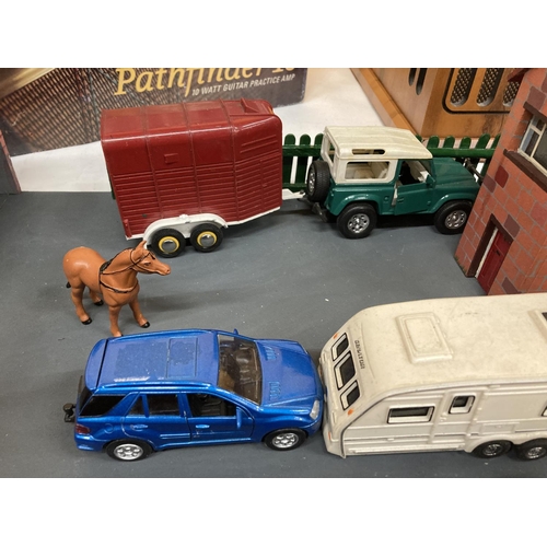 269 - A MODEL OF A FARMHOUSE AND STABLE BLOCK WITH A LANDROVER AND HORSEBOX AND A CAR AND CARAVAN