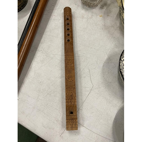 25A - A WOODEN FLUTE WITH CHIP. CARVED DECORATION LENGTH 32CM