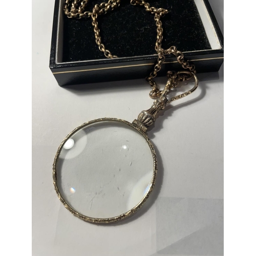 677 - A YELLOW METAL CHAIN WITH A DECORATIVE MAGNIFYING GLASS PENDANT IN A PRESENTATION BOX