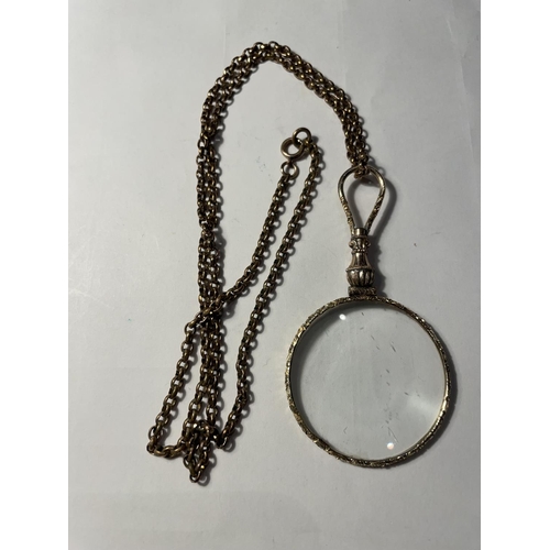 677 - A YELLOW METAL CHAIN WITH A DECORATIVE MAGNIFYING GLASS PENDANT IN A PRESENTATION BOX