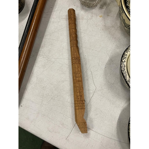 25A - A WOODEN FLUTE WITH CHIP. CARVED DECORATION LENGTH 32CM