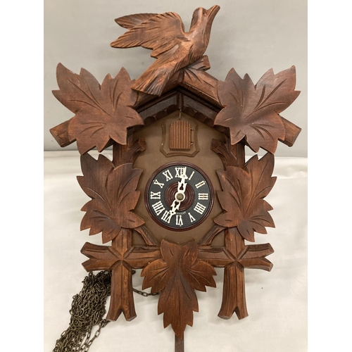 211 - A WOODEN CUCKOO CLOCK WITH PENDULUM AND CARVED LEAVES AND BIRD