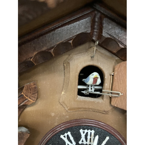 211 - A WOODEN CUCKOO CLOCK WITH PENDULUM AND CARVED LEAVES AND BIRD