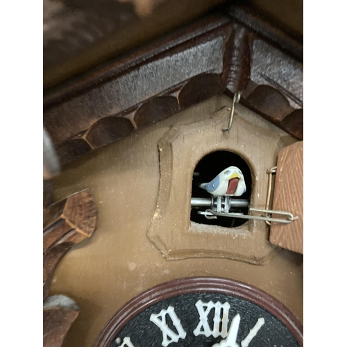 211 - A WOODEN CUCKOO CLOCK WITH PENDULUM AND CARVED LEAVES AND BIRD