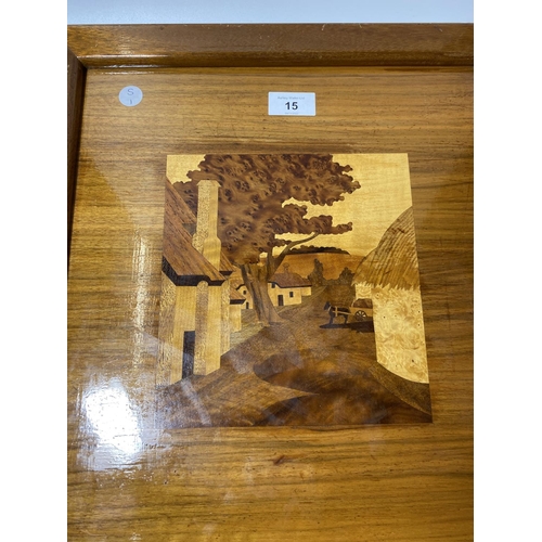 15 - AN A.H MCINTOSH INLAID WOODEN PLAQUE DEPICTING A VILLAGE SCENE