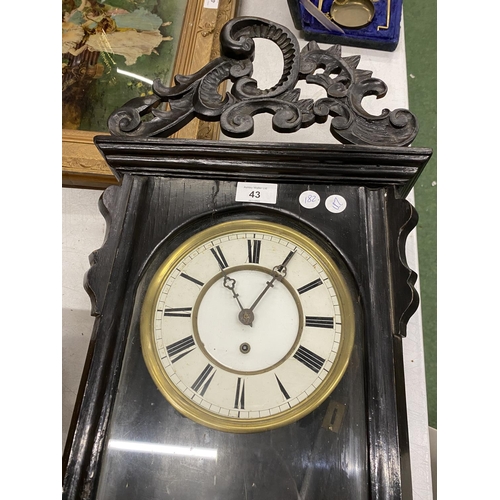 43 - A LARGE WALL CLOCK IN EBONISED CASE WITH CARVED TOP WITH PENDULUM AND WEIGHT