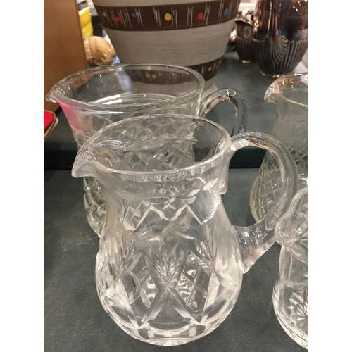 128 - FOUR VINTAGE GLASS WATER JUGS WITH ETCHED AND CUTGLASS DESIGN