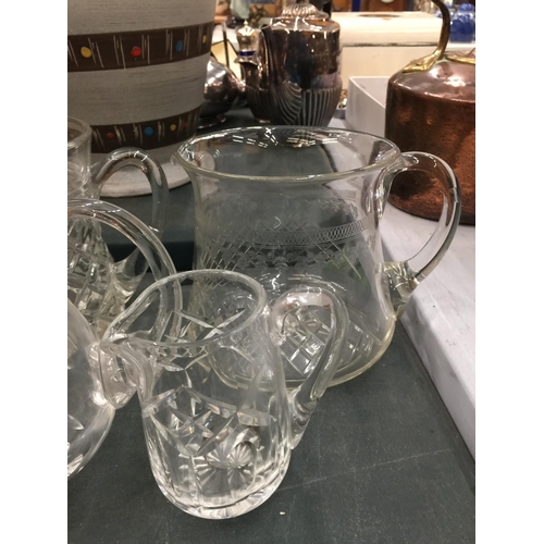 128 - FOUR VINTAGE GLASS WATER JUGS WITH ETCHED AND CUTGLASS DESIGN