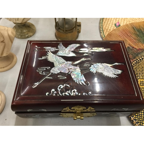 160 - AN ORIENTAL STYLE MUSICAL JEWELLERY BOX WITH CRIMSON LACQUER AND MOTHER OF PEARL STORK DECORATION