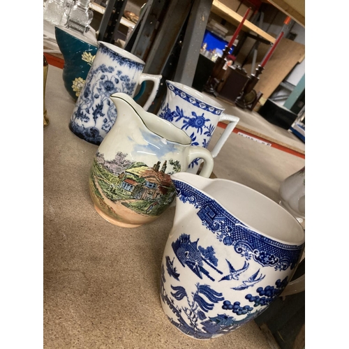 951 - A COLLECTION OF VINTAGE JUGS TO INCLUDE A ROYAL DOULTON WITH TRANSFER PRINTED SCENE - A/F, BLUE AND ... 