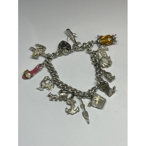 572 - A MARKED SILVER CHARM BRACELET WITH THIRTEEN CHARMS AND A HEART SHAPED CLASP