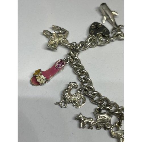 572 - A MARKED SILVER CHARM BRACELET WITH THIRTEEN CHARMS AND A HEART SHAPED CLASP