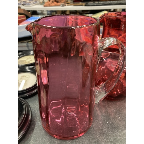 131 - A PAIR OF CRANBERRY GLASS JUGS HEIGHT 16CM