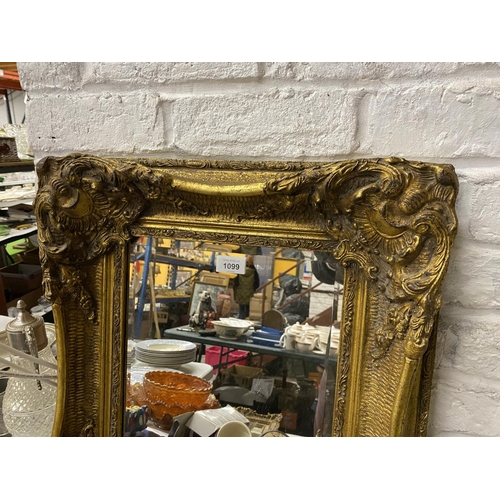 1099 - AN ORNATE RECTANGULAR GILT FRAMED MIRROR