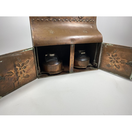 31 - AN ARTS AND CRAFTS 1912 COPPER DESKSTAND WITH LIFT UP TOP SECTION, TWO SMALL DRAWERS AND LOWER DOORS... 