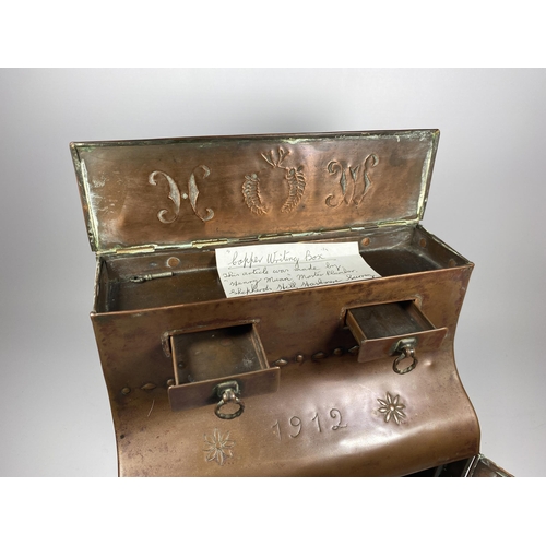 31 - AN ARTS AND CRAFTS 1912 COPPER DESKSTAND WITH LIFT UP TOP SECTION, TWO SMALL DRAWERS AND LOWER DOORS... 