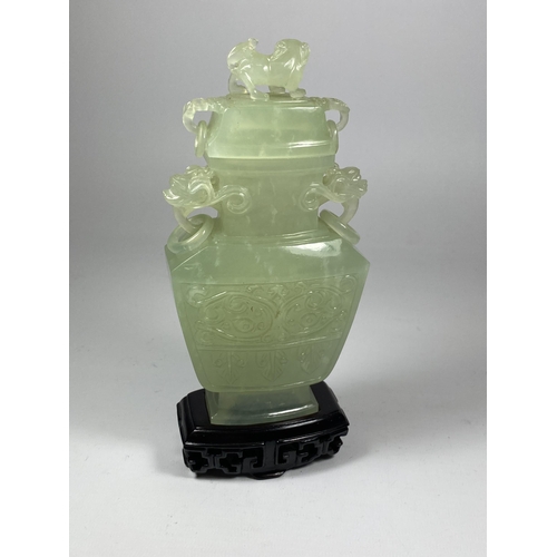 385 - A DECORATIVE ORIENTAL JADE TYPE HARDSTONE LIDDED VASE ON WOODEN BASE, HEIGHT 19CM