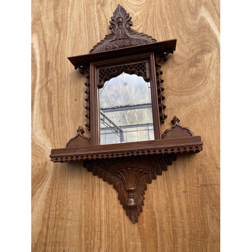 1210 - A DECORATIVE WOODEN FRAMED WALL MIRROR WITH LOWER SHELF