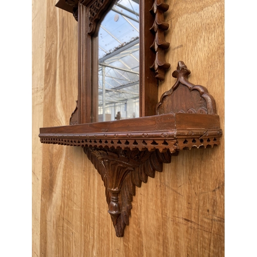 1210 - A DECORATIVE WOODEN FRAMED WALL MIRROR WITH LOWER SHELF