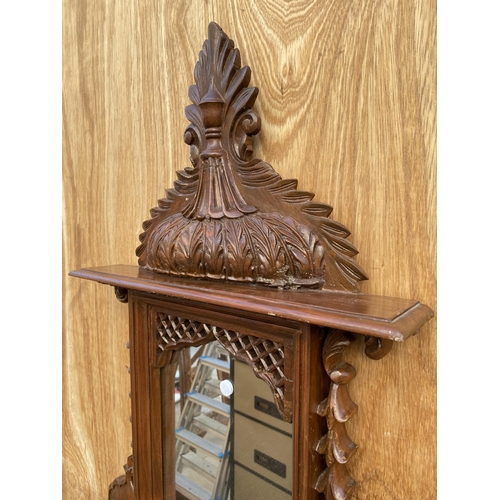 1210 - A DECORATIVE WOODEN FRAMED WALL MIRROR WITH LOWER SHELF