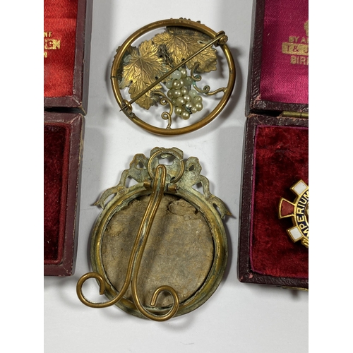 564 - A GROUP OF FOUR ITEMS TO INCLUDE TWO VINTAGE BOXED BADGES, GILT MINIATURE FRAME AND FLORAL GILT BROO... 