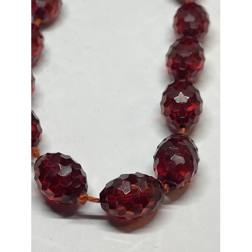 523 - AN AMBER EFFECT BEADED NECKLACE WITH TWENTY THREE BEADS AND TWO FASTNER BEADS