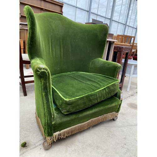 2375 - AN EDWARDIAN GREEN UPHOLSTERED ROUNDED WING-BACK EASY CHAIR ON CASTERS